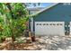 Side view of home's garage with lush foliage, landscaping, and attached air conditioner units at 2404 W Jetton Ave, Tampa, FL 33629