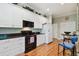 Kitchen with white cabinets, dark countertops, appliances, hardwood floors, and a breakfast area at 2404 W Jetton Ave, Tampa, FL 33629