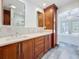 Bathroom with double vanity, wood cabinetry, and a luxurious soaking tub in the background at 2439 Madrid Ave, Safety Harbor, FL 34695