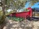 Exterior view of a home featuring a fenced dog run, landscaping, and vibrant red paint at 2439 Madrid Ave, Safety Harbor, FL 34695