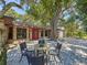 Brick home with red door and black shutters, features an outdoor seating area on a paver patio at 2439 Madrid Ave, Safety Harbor, FL 34695