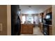 Kitchen featuring wood cabinets, black appliances, tile flooring, and a view of a chandelier lit dining area at 270 Planter Rd, Spring Hill, FL 34606