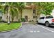 Townhouse exterior view featuring a front lawn, mature trees, colorful flower pots and parking at 2700 Bayshore Blvd # 544, Dunedin, FL 34698