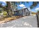 Charming gray home featuring a bright blue door, mature trees, and a freshly poured concrete driveway at 2859 38Th N Ave, St Petersburg, FL 33713