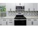 Close-up of a modern kitchen with white cabinets, stainless steel appliances, granite countertops, and backsplash at 2859 38Th N Ave, St Petersburg, FL 33713