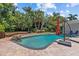 Backyard pool featuring a wood deck, stone accents, lush landscaping and a spacious paver patio at 3012 Grand View Ave, Clearwater, FL 33759