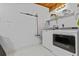 Bright laundry room with modern white washer and dryer set, white tile flooring, and storage shelves at 3012 Grand View Ave, Clearwater, FL 33759