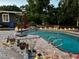 Inviting backyard pool area with stone accents, night lighting and tropical foliage at 3012 Grand View Ave, Clearwater, FL 33759