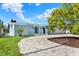 Charming blue home featuring an arched entryway, paver driveway, well-manicured lawn, and mature landscaping at 304 Westwinds Dr, Palm Harbor, FL 34683