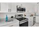 Modern kitchen with stainless steel appliances, white cabinetry, and sleek countertops, offering a clean and stylish cooking space at 304 Westwinds Dr, Palm Harbor, FL 34683
