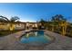 Backyard pool illuminated at dusk with a paver deck and a cozy outdoor dining space at 309 Palmetto Ln, Largo, FL 33770