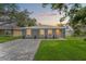 Charming single-story home with gray exterior, well-manicured lawn, and brick driveway at sunset at 3135 W Varn Ave, Tampa, FL 33611