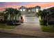 Striking two-story home at twilight features a paved driveway, two-car garage, and tropical landscaping at 315 Blackrock Ln, Apollo Beach, FL 33572