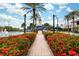Walkway to community pool features vibrant flowers, mature trees and a lighthouse themed water slide under a blue sky at 315 Blackrock Ln, Apollo Beach, FL 33572