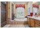 Relaxing bathroom with a garden tub, separate shower, wood cabinetry, and decorative window at 33744 Americana Ave, Dade City, FL 33525