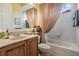 Well-lit bathroom featuring a vanity, marble countertop, and tub with decorative shower curtain at 33744 Americana Ave, Dade City, FL 33525