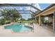 Inviting pool in screened lanai, features hot tub, lounge chairs, and beautiful golf course views at 33744 Americana Ave, Dade City, FL 33525