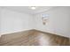 A small bedroom featuring wood-look flooring, white walls, a window with an AC unit, and a ceiling light at 3502 King Richard Ct, Seffner, FL 33584