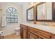 Bathroom with double sinks, warm wood vanity, attractive mirror, and arched window bringing in natural light at 37147 Foxrun Pl, Zephyrhills, FL 33542
