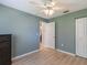Bedroom featuring wood-look floors, a ceiling fan, an attractive blue accent wall and a window at 37147 Foxrun Pl, Zephyrhills, FL 33542