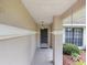 Front entrance showcasing a covered porch, decorative light fixture, and manicured landscaping at 37147 Foxrun Pl, Zephyrhills, FL 33542