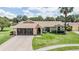 Well-maintained home with a lush lawn, mature trees, screened in garage, and an American flag waving proudly at 37147 Foxrun Pl, Zephyrhills, FL 33542