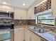 Close up of kitchen featuring stainless steel appliances, backsplash, and sink with window at 37147 Foxrun Pl, Zephyrhills, FL 33542