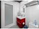 Modern bathroom featuring a vibrant red vanity, illuminated mirror, and clean white tiles, creating a stylish and functional space at 4050 4Th N St # 116, St Petersburg, FL 33703