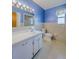 Bathroom with blue walls featuring a vanity, a toilet, and shower at 5004 S Hesperides St, Tampa, FL 33611