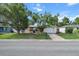 Street view of a single-story home with an attached garage, mature trees, and a well-maintained lawn at 7040 Fox Hollow Dr, Port Richey, FL 34668