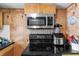 Efficient black stove with stainless steel microwave and wood paneling at 7040 Fox Hollow Dr, Port Richey, FL 34668