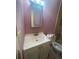 Modest bathroom featuring a vanity, toilet, and framed mirror over a sink, with pink walls at 7192 E Bank Dr, Tampa, FL 33617