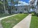 Exterior of a two-story townhouse featuring green grass, sidewalks, and trees at 7192 E Bank Dr, Tampa, FL 33617
