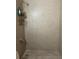 Shower with beige tiling and a showerhead with a metal shelving unit at 7192 E Bank Dr, Tampa, FL 33617