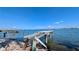 View of a partially collapsed pier extending into clear blue water, set against a backdrop of a distant cityscape at 720 Boca Ciega Isle Dr, St Pete Beach, FL 33706