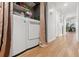 Hallway featuring a linen curtain and leading to a laundry area with white appliances and wood floors at 7614 Radcliffe Cir # 202B, Port Richey, FL 34668