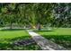 Playground surrounded by mature trees, lush grass, and park walkway at 811 W Peninsular St, Tampa, FL 33603