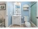 A serene blue bathroom featuring a white vanity, mirror, and shower with glass doors at 835 Symphony Isles Blvd, Apollo Beach, FL 33572