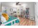 Well-lit bedroom featuring modern desk and chair, bookcase, and laminate flooring at 835 Symphony Isles Blvd, Apollo Beach, FL 33572