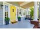 Inviting front porch with bright yellow door, bench seating, potted plants, and brick foundation at 842 S Boulevard, Tampa, FL 33606