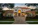 Elegant home exterior with lush landscaping, circular driveway, and well-lit facade, perfect for evening appeal at 8476 Dunham Station Dr, Tampa, FL 33647