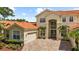 Elegant home features an arched entryway, terracotta roof, well-manicured landscaping, and brick driveway at 8476 Dunham Station Dr, Tampa, FL 33647