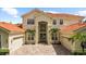 Well-maintained home featuring a brick driveway, three-car garage, and tropical landscaping at 8476 Dunham Station Dr, Tampa, FL 33647