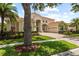 Inviting home with terracotta roof, lush landscaping, mature trees and a brick driveway at 8476 Dunham Station Dr, Tampa, FL 33647