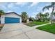 Charming home featuring a well-manicured lawn, blue garage door, and mature palm trees at 8635 Chadwick Dr, Tampa, FL 33635