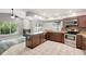 Open kitchen has stainless steel appliances, wood cabinets, and views of living area and pool at 8635 Chadwick Dr, Tampa, FL 33635