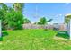 A spacious backyard featuring a wooden fence, lush green grass, and a small patio set perfect for outdoor relaxation at 10436 117Th Dr, Largo, FL 33773