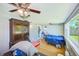 Cozy bedroom featuring hardwood floors, ceiling fans, a large window with natural light, and an armoire at 10436 117Th Dr, Largo, FL 33773
