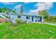 Well-kept single-story home featuring a blue exterior, lush green lawn, and inviting front entrance at 10436 117Th Dr, Largo, FL 33773