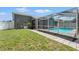 This grassy backyard has a screened in pool and is bordered by a white wooden fence at 10032 Basin St, New Port Richey, FL 34655